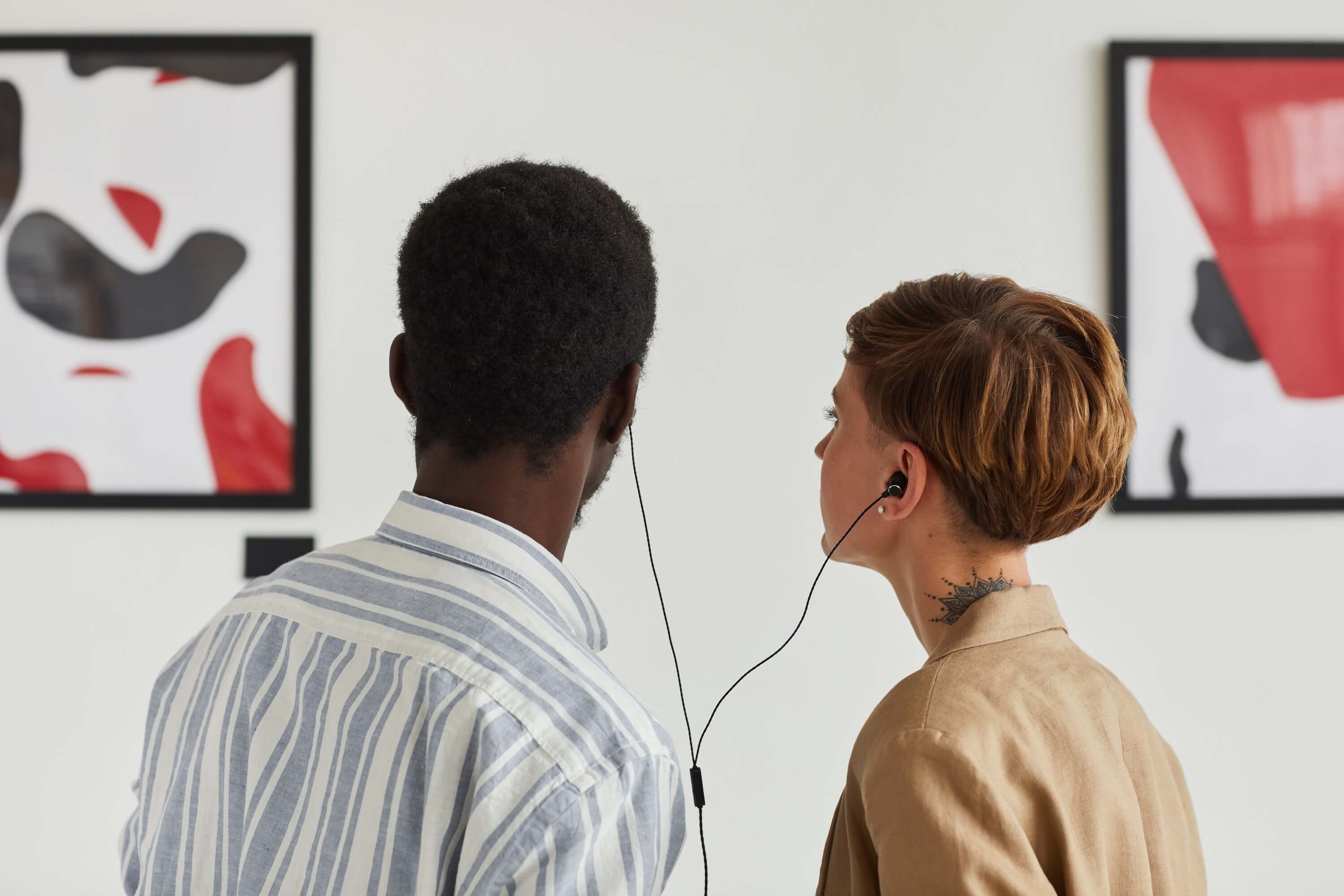 two people sharing an audio tour in an art gallery